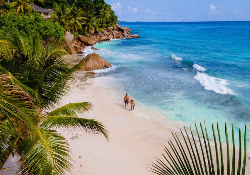 Anse Patates, La Digue Seychelles, a young couple of men and women on a tropical beach during a luxury vacation in Seychelles. Tropical beach Anse Patates, La Digue Seychelles