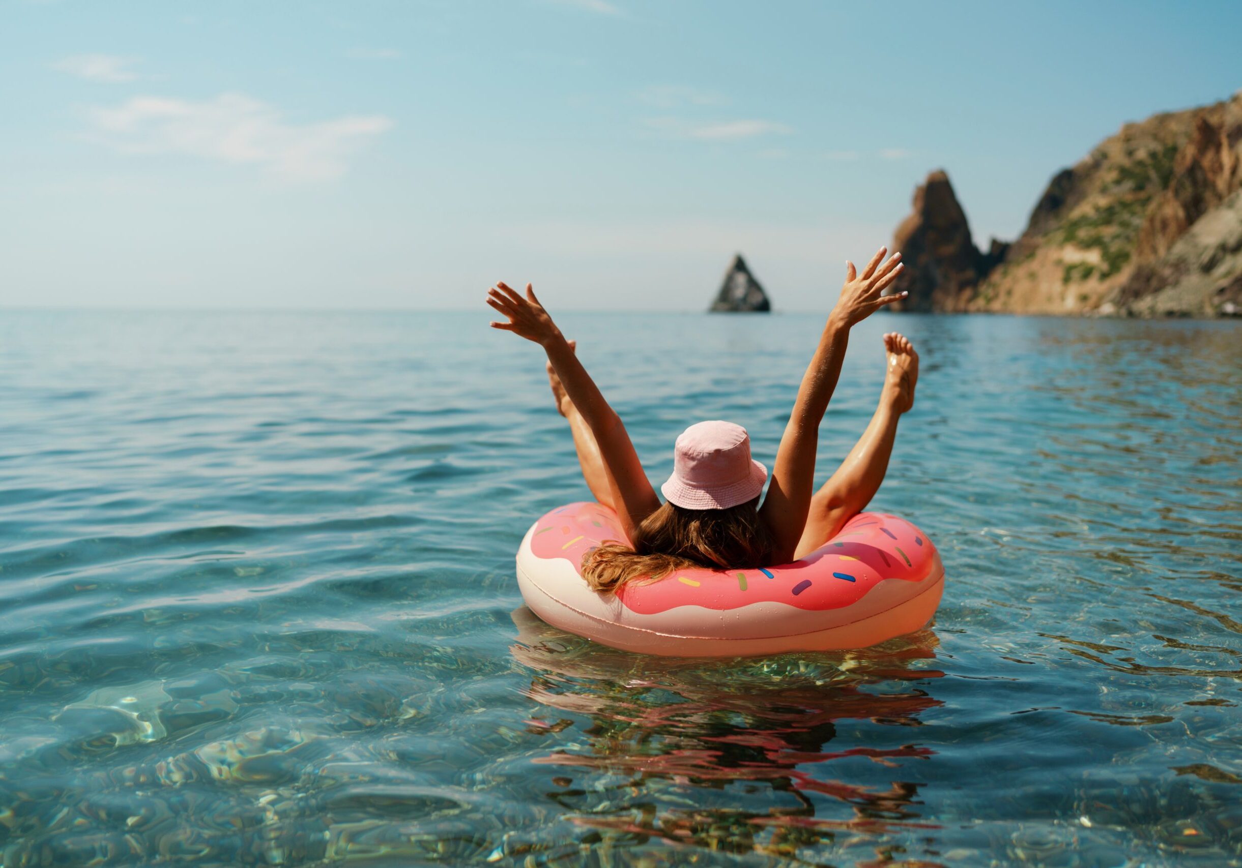 Summer vacation woman in hat floats on an inflatable donut mattress. Happy woman relaxing and enjoying family summer travel holidays travel on the sea